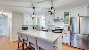 A modern kitchen with white cabinets, a large island with bar stools, stainless steel appliances, and pendant lighting. - Cozy North Carolina Retreat Near Fishing & Boating (Washington)