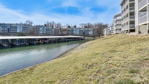 A riverside view of a modern apartment complex with a covered walkway along the water. - Regatta Bay Condo w/ Balcony + Water Views! (Lake Ozark)