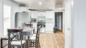 A modern kitchen with white cabinets, a stainless steel refrigerator, and a dining table with chairs. - Charming El Dorado Retreat Near Main Street! (El Dorado)