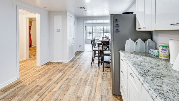 A spacious kitchen with a granite countertop, a refrigerator, and a dining area with chairs and a table. - Charming El Dorado Retreat Near Main Street! (El Dorado)