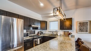 A modern kitchen with stainless steel appliances, granite countertops, and dark cabinetry. - Downtown Winter Park Condo w/ Free Bus to Ski Base (Winter Park)