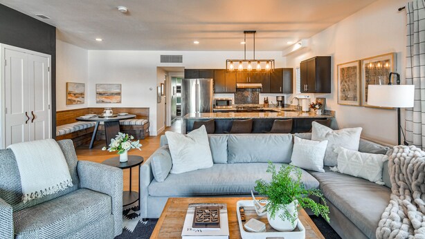 A modern living room with a grey sofa, a coffee table, and a dining area with a bench. - Downtown Winter Park Condo w/ Free Bus to Ski Base (Winter Park)