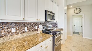 A kitchen with white cabinets, a granite countertop, a microwave, and an oven. - Cozy Cape Coral Home: 8 Mi to Marina! (Cape Coral)