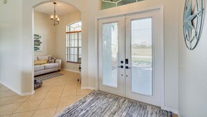 A spacious entryway with a large door, a chandelier, and a decorative wall piece. - Cozy Cape Coral Home: 8 Mi to Marina! (Cape Coral)