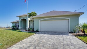 A single-story house with a garage, a front lawn, and an American flag. - Cozy Cape Coral Home: 8 Mi to Marina! (Cape Coral)