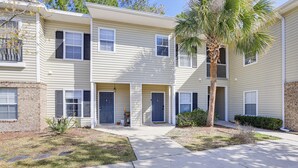 A multi-story apartment building with a central entrance, a palm tree, and a brick facade.