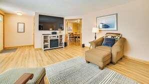 Un salon avec un canapé, un pouf et un meuble pour la télévision.