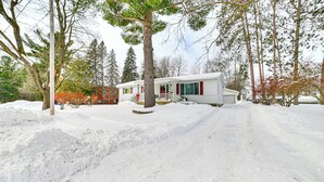 Un paysage enneigé avec une maison mobile et un grand arbre au premier plan.