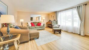 Un salon comprenant un canapé, un pouf, un fauteuil et un piano.