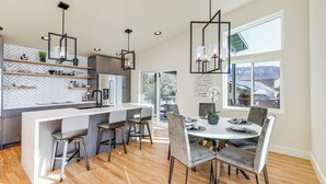 A modern kitchen with a central island, bar stools, and pendant lighting. - Hot Tub & Panoramic Mtn Views: Pine Retreat! (Pine)