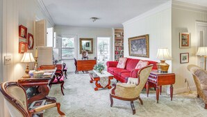 Una sala de estar tradicional con un sofá rojo, muebles de madera y una estantería.