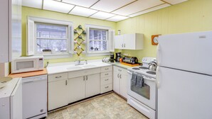 Una cocina con armarios blancos, un microondas, una estufa y un refrigerador.