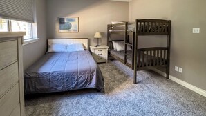 Un dormitorio con una cama individual, una mesita de noche, una lámpara, una cama litera y un ventilador de techo.