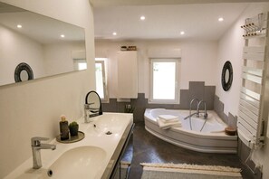 Un baño moderno con un lavamanos grande, una bañera y un espejo.