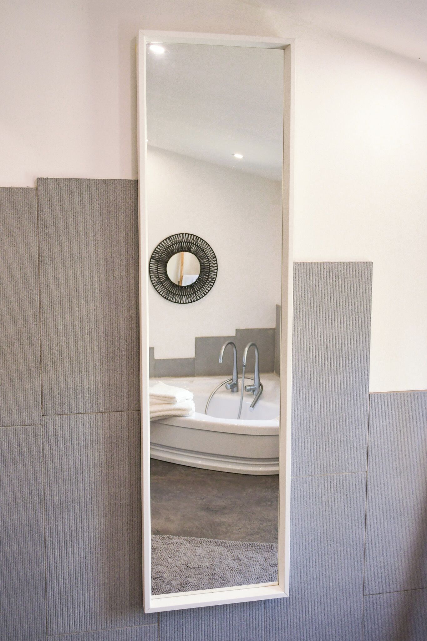 Une salle de bain avec un grand miroir, un élément décoratif rond fixé au mur et un lavabo moderne.