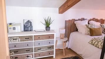Ein Schlafzimmer mit einem Bett, einem Nachttisch, einer kleinen weißen Lampe, einem Radio, einem gerahmten Bild und einer Pflanze.
