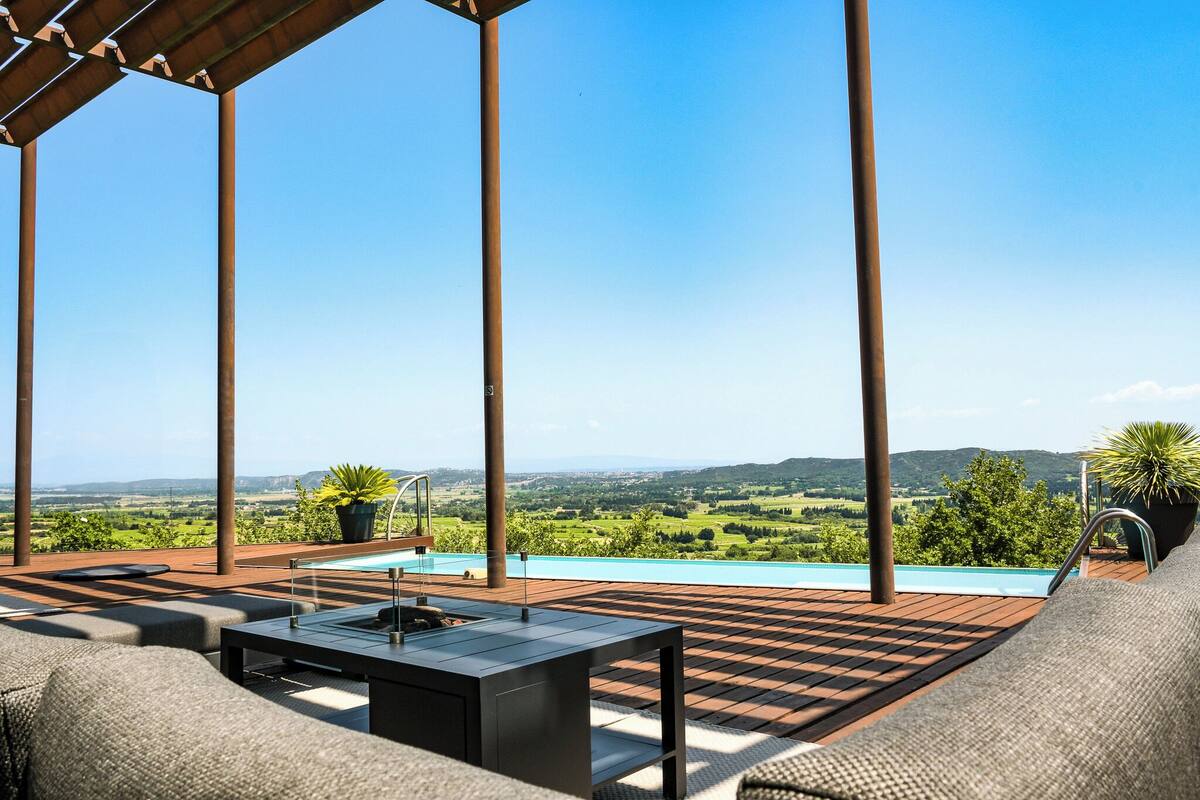 Een dakterras met zwembad, buitenmeubilair en uitzicht over het platteland.