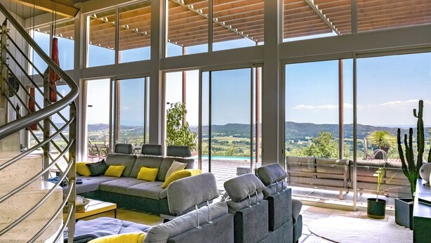 A spacious living area with a large window overlooking a scenic landscape, a built-in sofa, and a staircase.