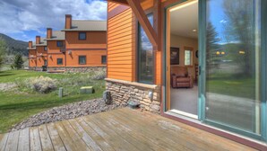 Una casa moderna con terraza, amplios ventanales correderas y base de piedra.