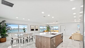 A modern kitchen with a large island, white marble flooring, and large windows overlooking a body of water. - Luxury condo with stunning intracoastal water views, near downtown West Palm Bch (West Palm Beach)