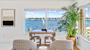 A room with a large window overlooking a marina, a dining table with chairs, and a potted plant. - Luxury condo with stunning intracoastal water views, near downtown West Palm Bch (West Palm Beach)