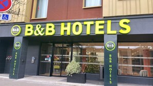 Het uiterlijk van B&B Hotels, met een duidelijke ingang, een rolstoeltoegankelijkheidsbord en een kerstboomdecoratie.