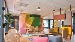 Een moderne lounge met zitopstelling, een kleurrijke muur en een plafond met inbouwverlichting.