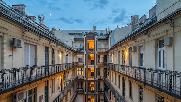 Un edificio a più piani con una scalinata centrale, balconi e un cortile interno.