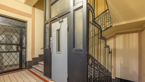 L'ingresso di un edificio con un cancello in metallo, una porta e una scala con ringhiere decorate.