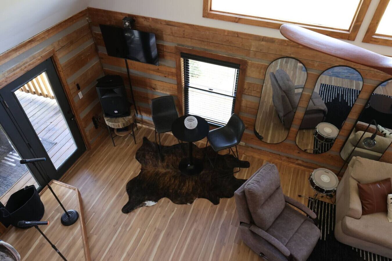 Ein gemütliches Blockhaushaus-Interieur mit Holzboden, einem zentralen Tisch mit Stühlen, einem großen Spiegel und einer Couch.