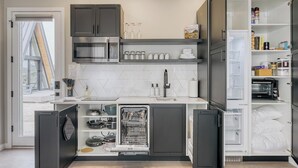 Een moderne keuken met inbouwapparatuur, waaronder een vaatwasser, oven en magnetron.