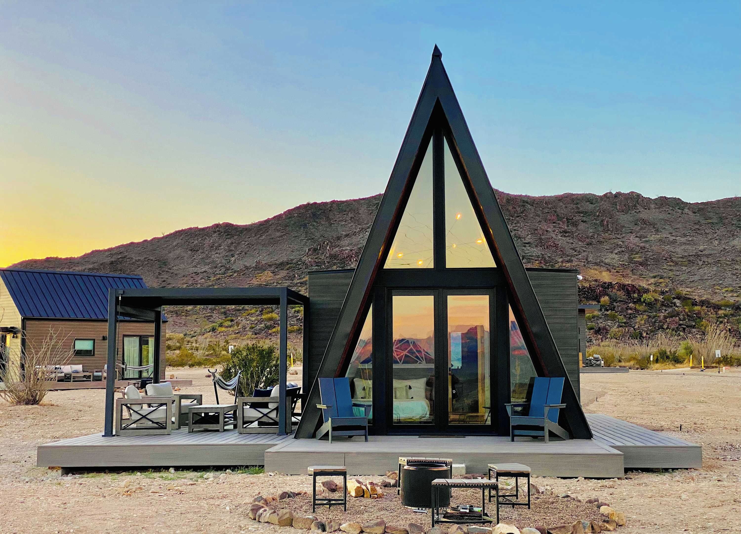 Um edifício moderno, de formato triangular, com terraço e área de estar ao ar livre.