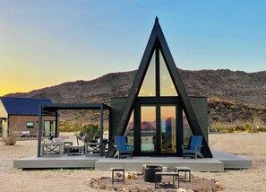 A modern, triangular-shaped building with a deck and outdoor seating area. - Stardust Big Bend Luxury A-Frame#1 with a fab view (Terlingua)