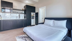 A modern bedroom with a large bed, a built-in wardrobe, and a kitchenette with a microwave and refrigerator. - Stardust Big Bend Luxury A-Frame#10 with fab view (Terlingua)