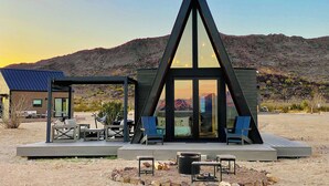 Un bâtiment moderne de forme triangulaire, doté d’une terrasse et d’un espace extérieur aménagé pour s’asseoir.