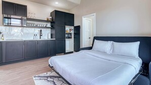 Une chambre moderne dotée d’un grand lit, d’une armoire intégrée et d’une kitchenette équipée d’un four à micro-ondes et d’un réfrigérateur.