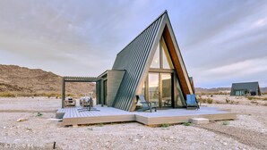 A modern, triangular-shaped building with a wooden deck and outdoor seating.