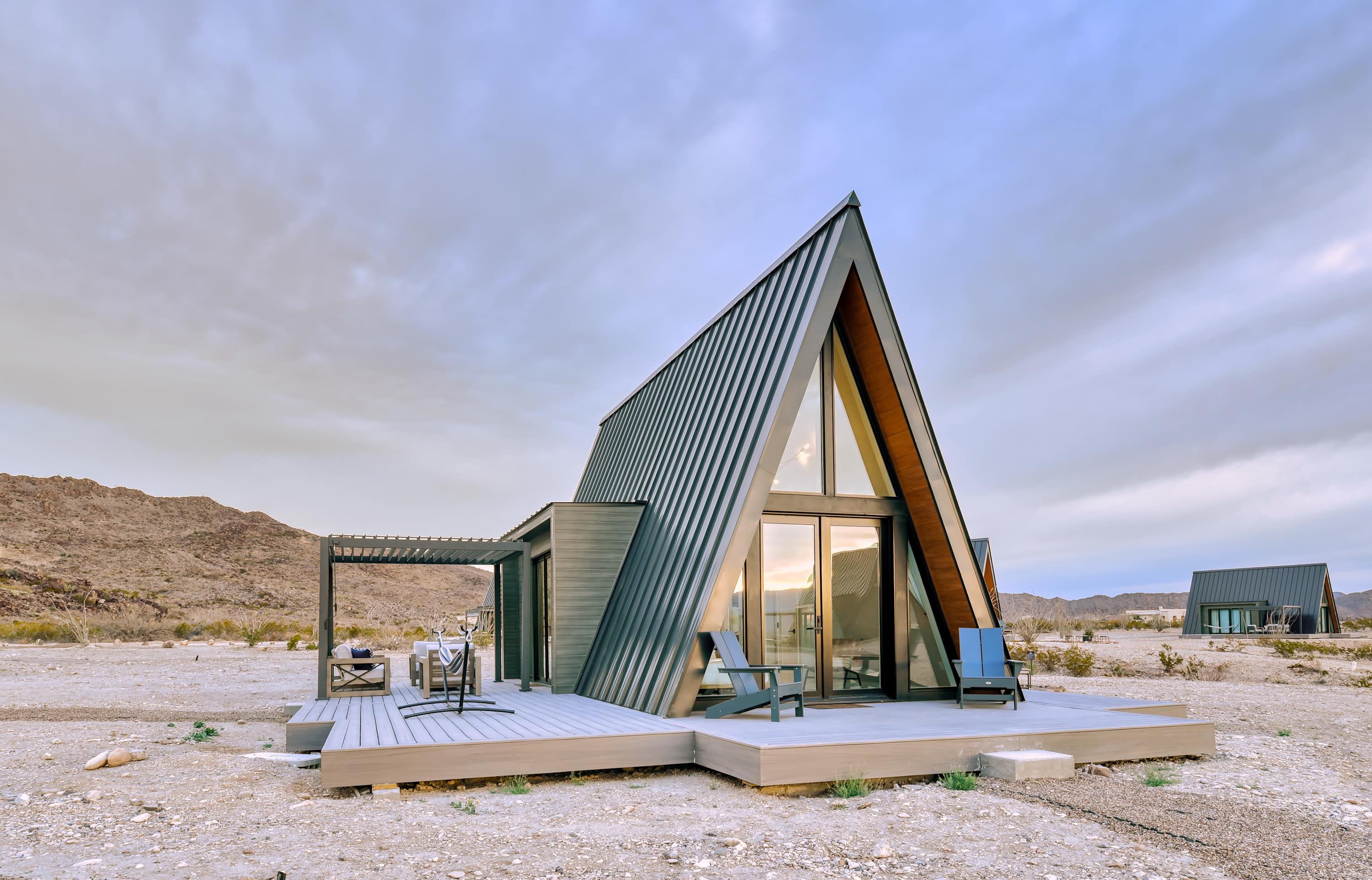 A modern, triangular-shaped building with a wooden deck and outdoor seating.