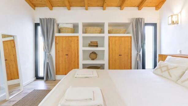 Un dormitorio con una cama grande, armarios de madera y vistas al exterior.