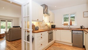 Een moderne keuken met witte kastjes, houten aanrecht, een ingebouwde oven en een vaatwasser.