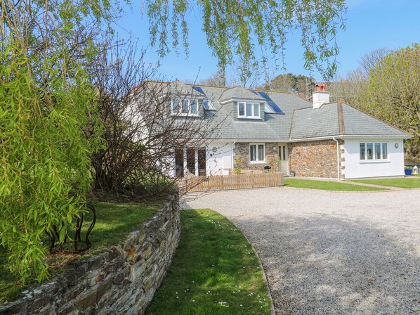 A stone house with a gravel driveway and a wooden fence.