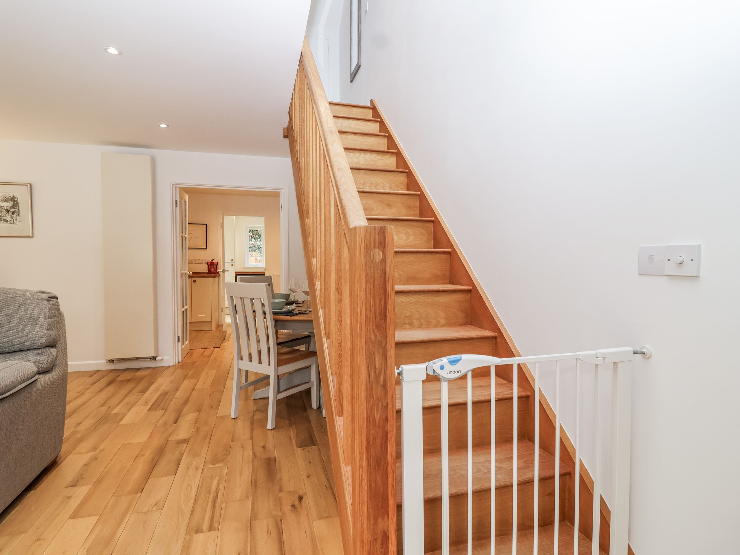 A modern interior with a wooden staircase, a dining area, and a living room with a sofa.