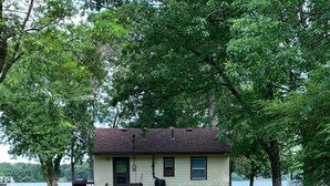 A single-story house with a front porch, a small deck, and a visible water tank.