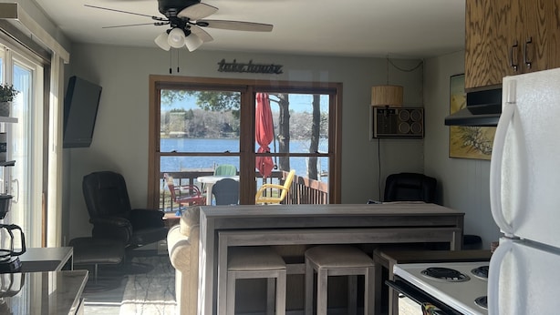A modern kitchen with a central island, a dining area with chairs, and a view of the outdoors.