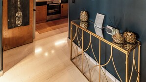 A modern kitchen with wooden cabinets, a red accent wall, and a gold console table with decorative items. - Mimosa Urban Habitation  (Chania)