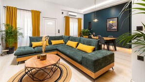 A modern living room with a sectional sofa, a wooden coffee table, and a dining area with a table and chairs. - Mimosa Urban Habitation  (Chania)