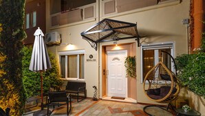 A hotel entrance with a white door, a hanging chair, and outdoor seating. - Mimosa Urban Habitation  (Chania)