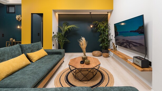 A modern living room with a green sofa, a wooden coffee table, and a large flat-screen TV mounted on the wall. - Mimosa Urban Habitation  (Chania)