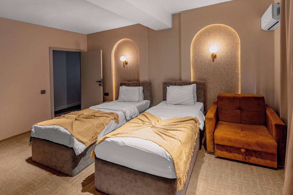 Une chambre d’hôtel avec deux lits, un canapé et un climatiseur fixé au mur.