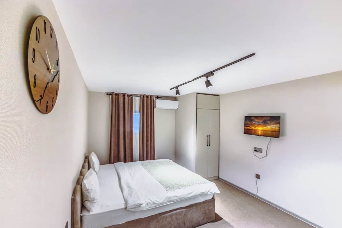 Une chambre à coucher avec un lit, une horloge, une télévision et une armoire.